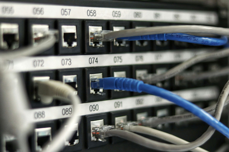 Closeup photograph of cable management system numbered and grey and blue network cables going into ports.